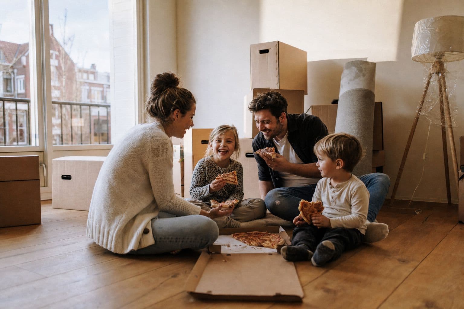 Gezin eet pizza tussen de verhuisdozen in hun nieuwe huis